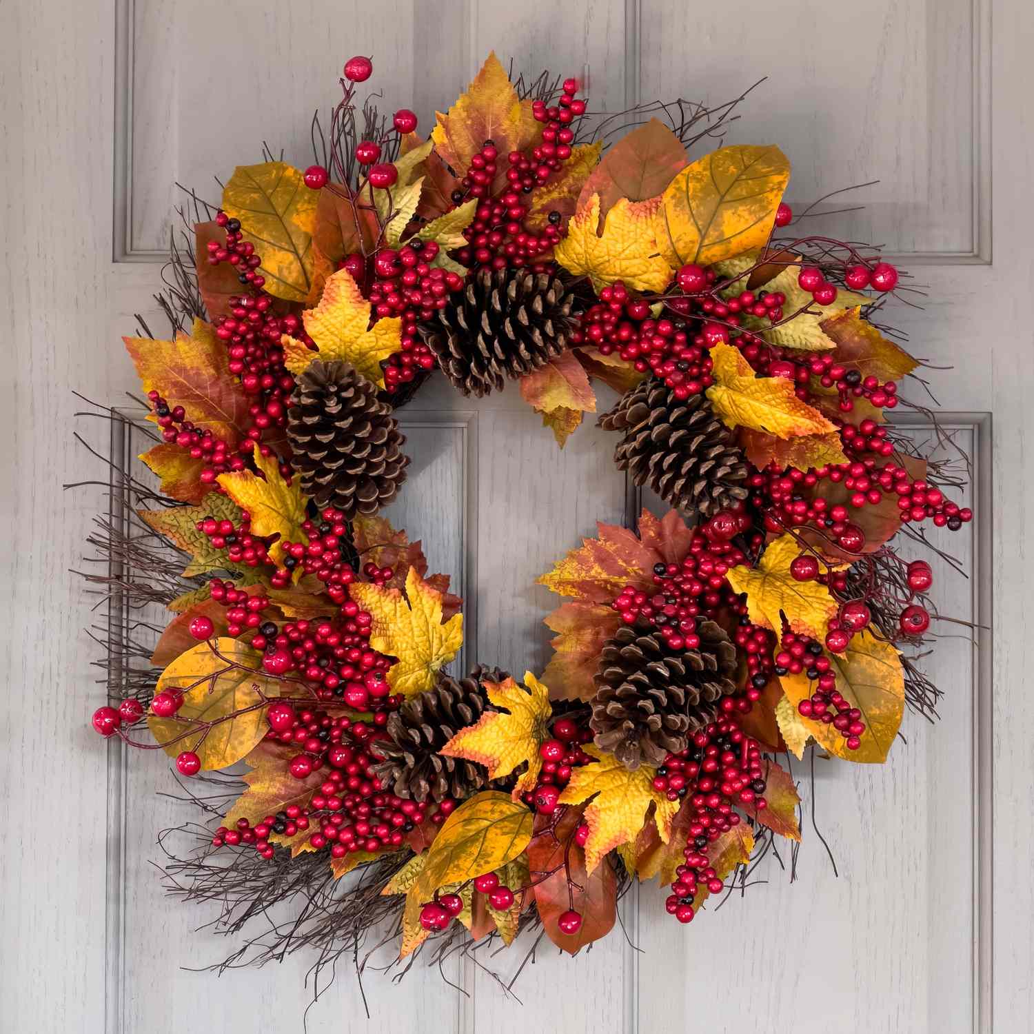 A wreath with pinecones red berries and fall leaves