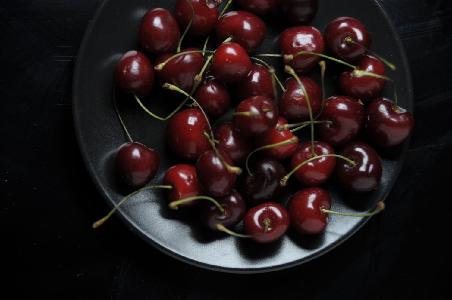 black cherries on grey dish with dark background