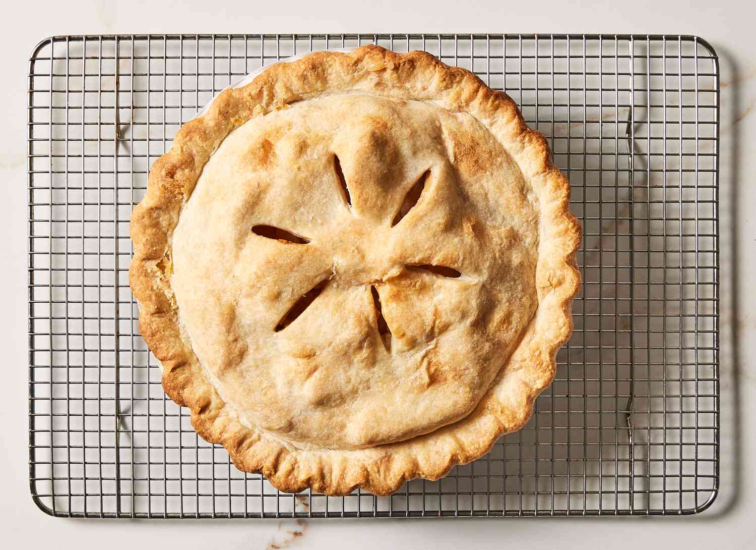 overhead view of baked apple pie cooking on a wire rack