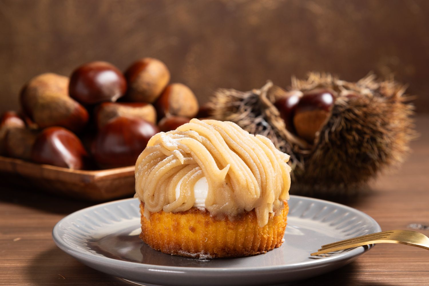 A Mont Blanc dessert on a plate with chestnuts and a spiky chestnut shell in the background