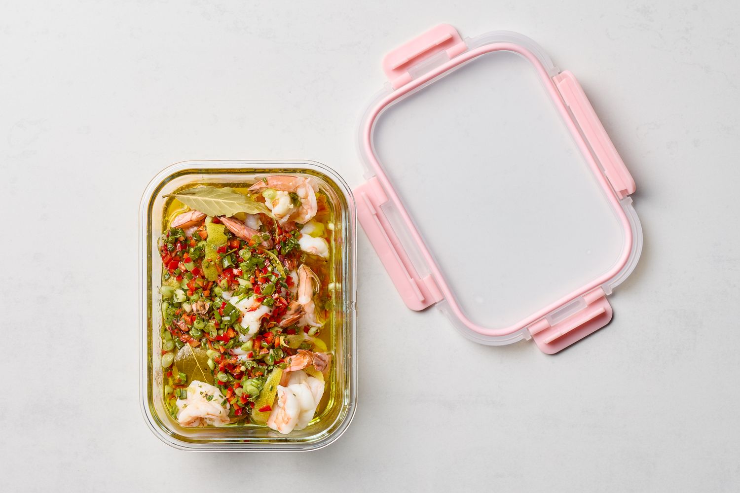 A container with pickled shrimp herbs and diced chiles cover beside it