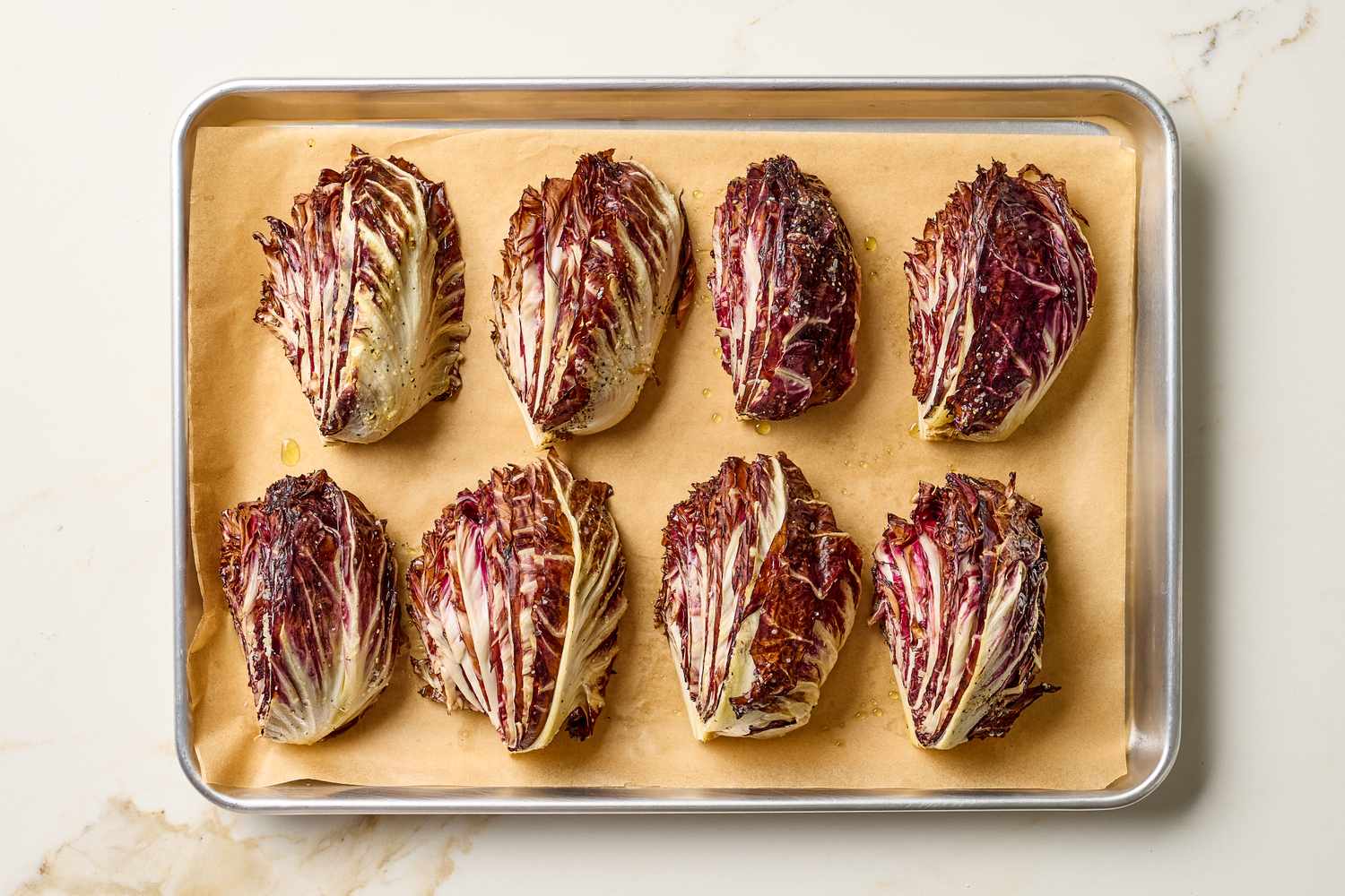 Tray of roasted radicchio halves arranged on parchment paper