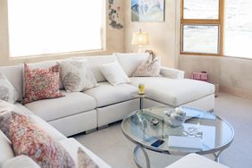 Modern living room with a sectional sofa glass coffee table and large windows providing natural light
