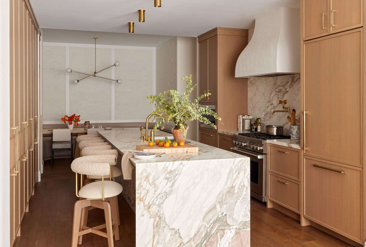 Modern kitchen with a marble island wooden cabinets stools and contemporary lighting fixtures