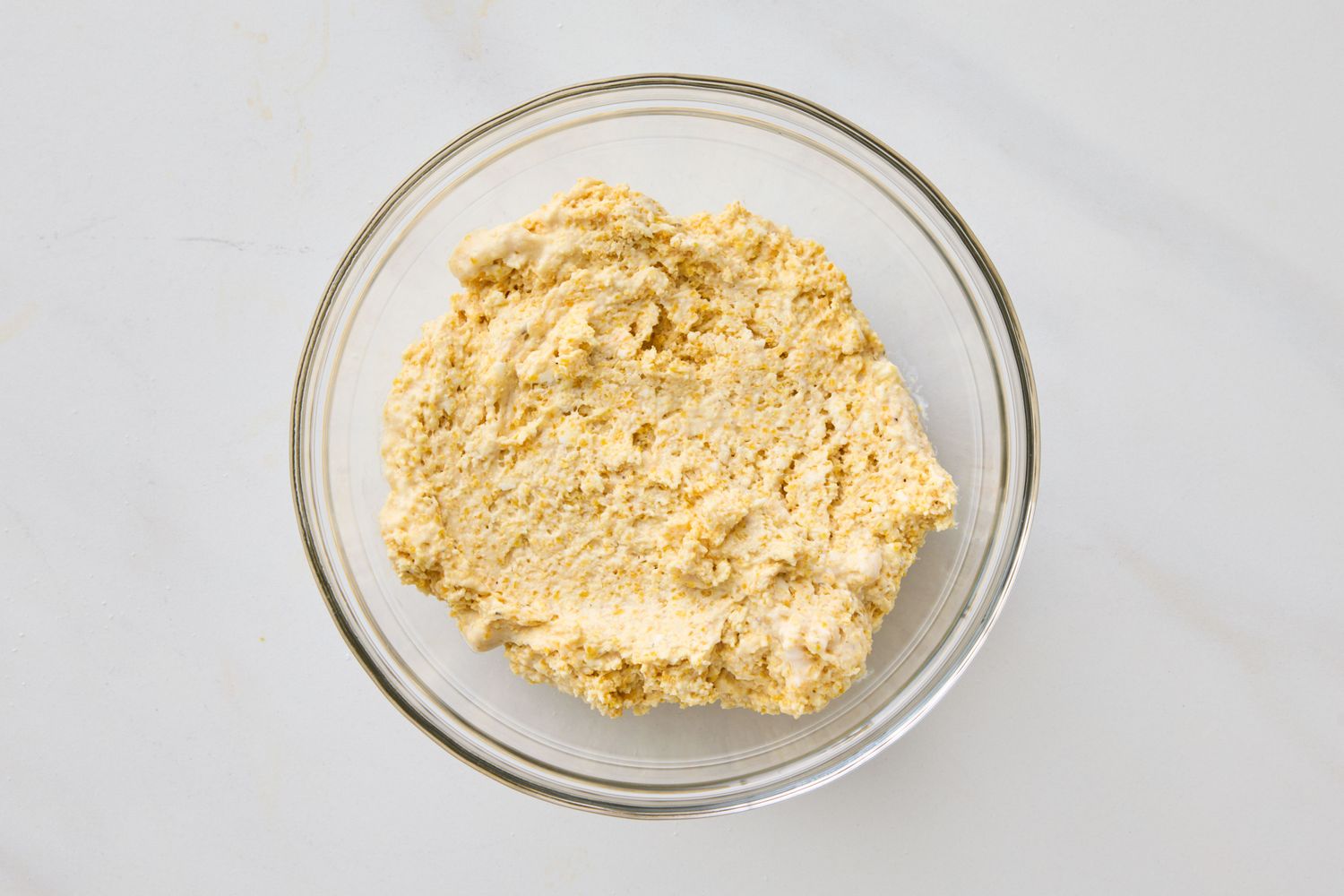 A bowl of dough on a white countertop