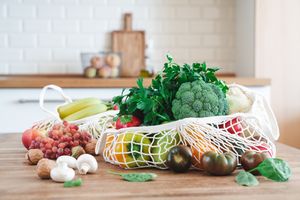 A producefilled mesh bag on a wooden kitchen counter