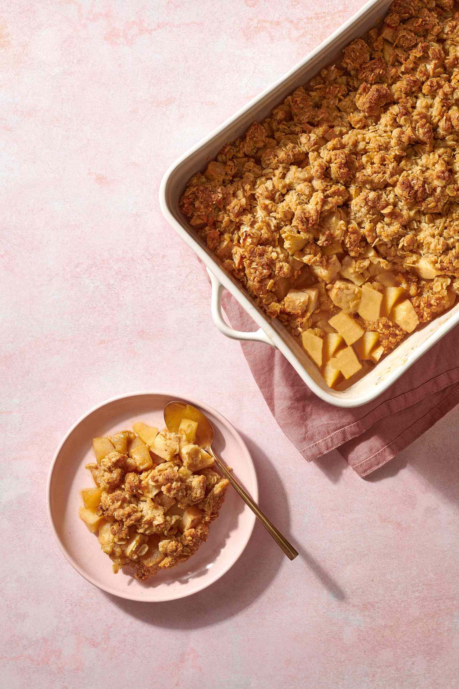 portion of apple crisp on plate and apple crisp in baking dish