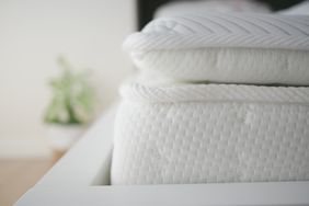 A closeup view of a stacked mattress and pillow on a bed frame