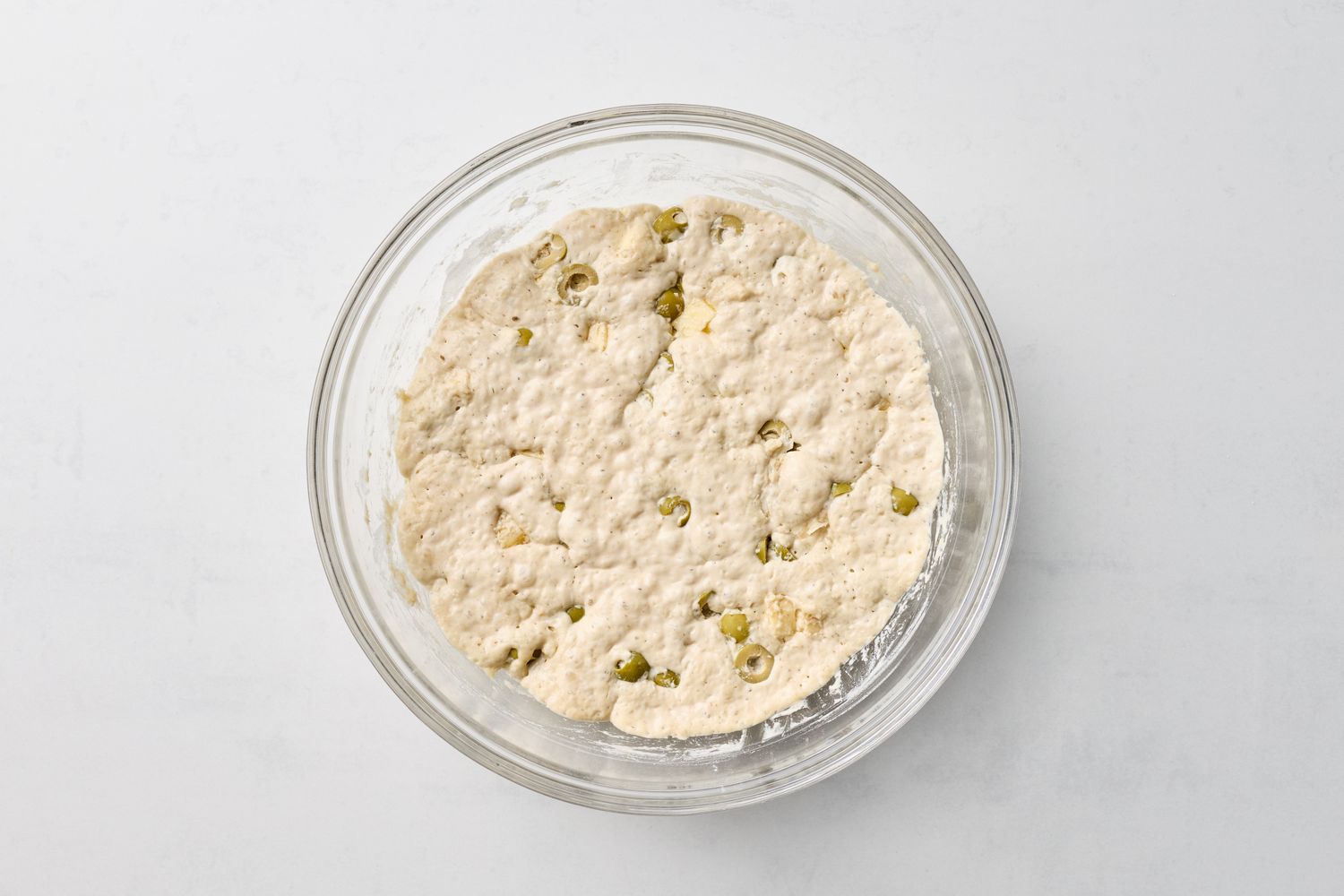 Dough with green olives in a mixing bowl