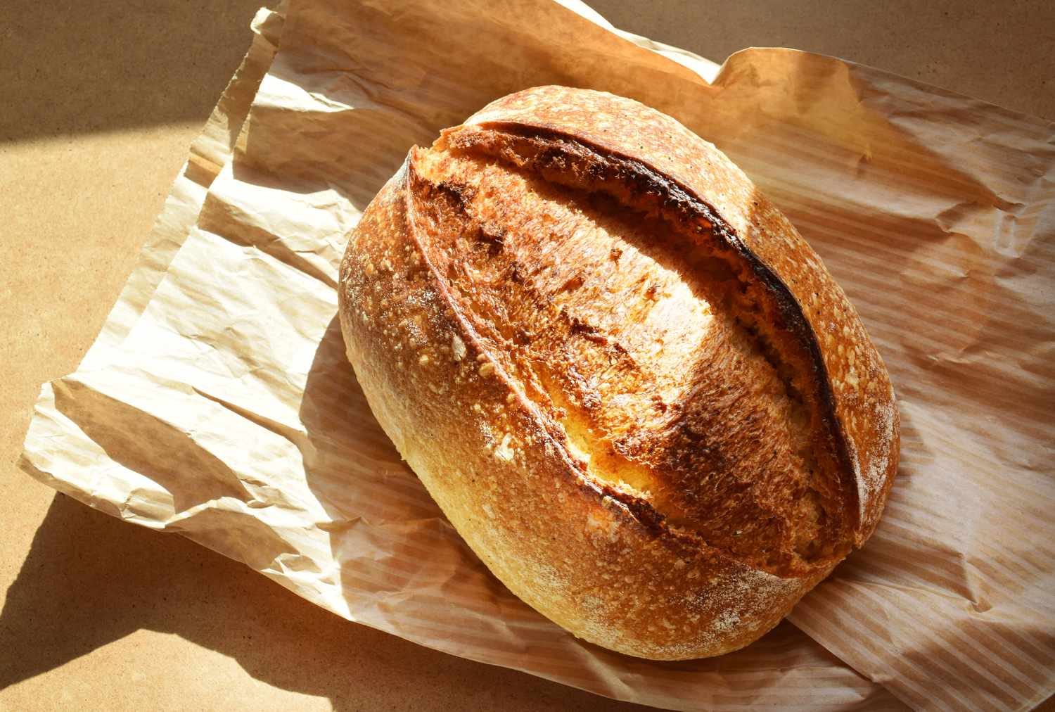 A loaf of sourdough bread on a crumpled paper bag