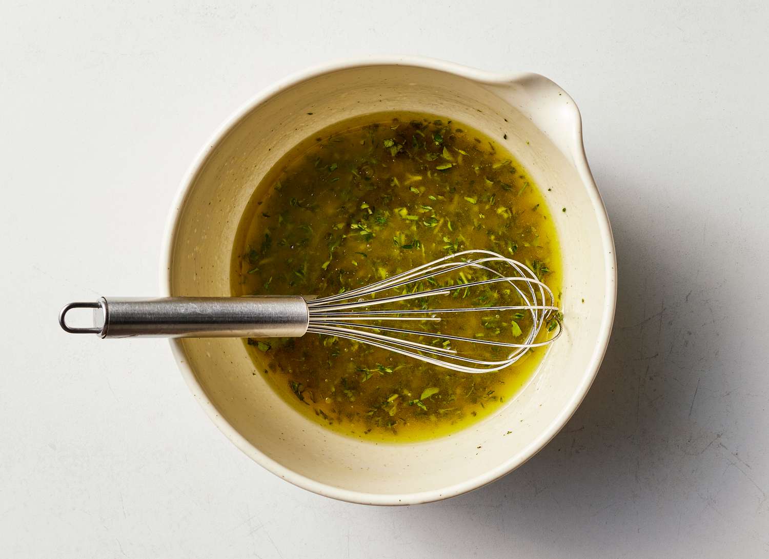 bowl of garlic and herbs with a wisk