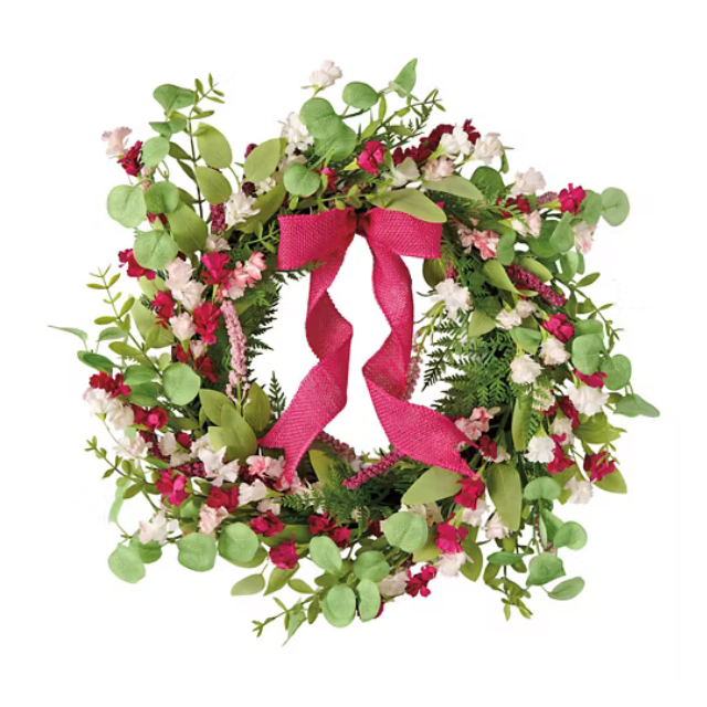 A decorative wreath adorned with leaves flowers and a red ribbon bow