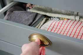 close up of a woman pulling a grey dresser drawer open