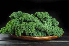 kale leaves in shallow wooden bowl with dark background