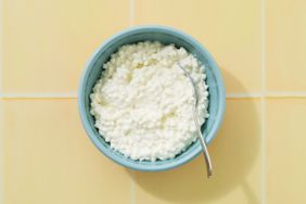 A bowl of cottage cheese with a spoon on a tiled surface