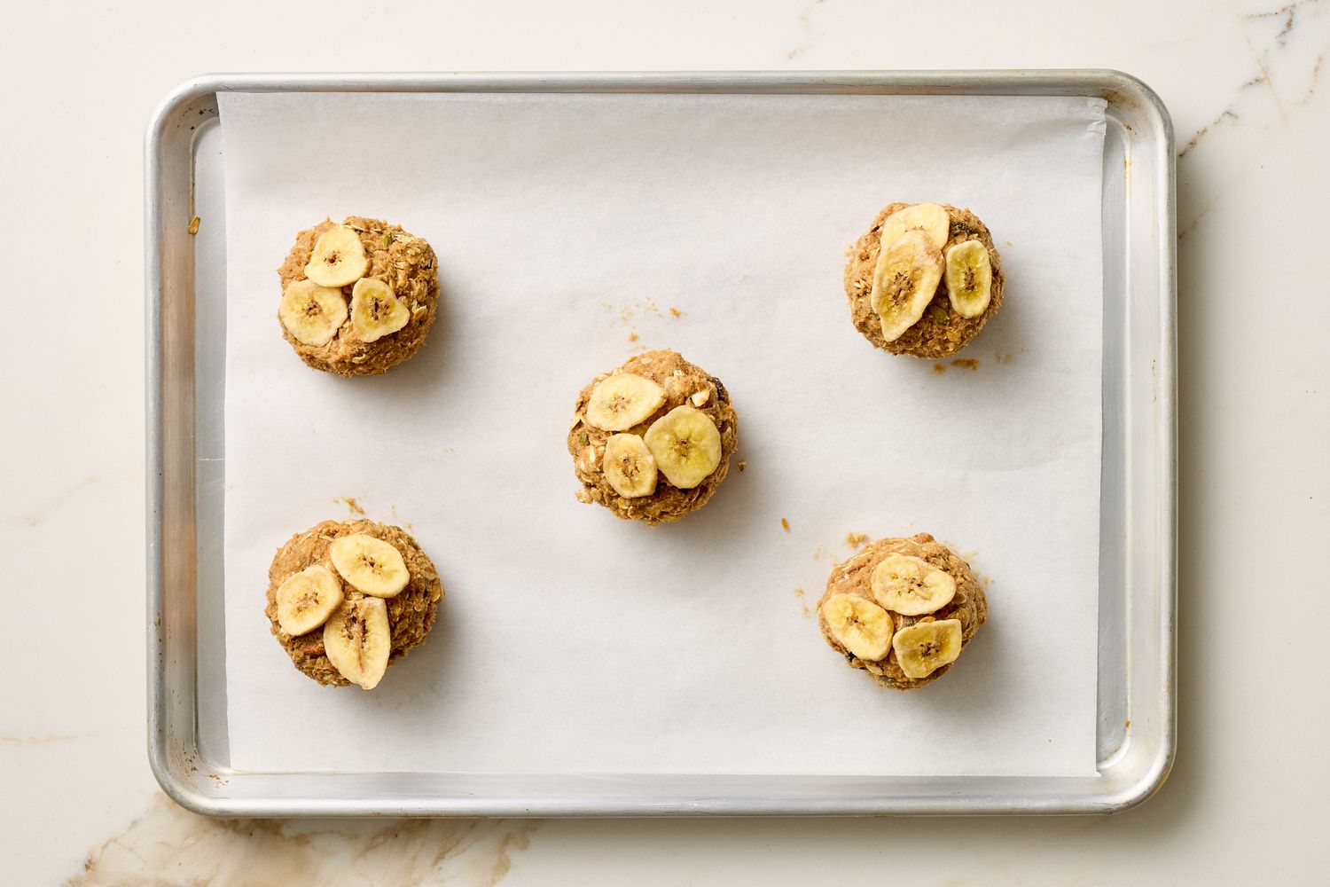 Tray of bananatopped breakfast cookies on parchment paper