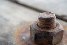 Closeup of a rusty bolt and nut on a wooden surface