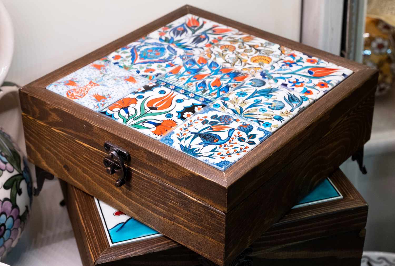 A wooden box with a decorative ceramic tile design on the lid