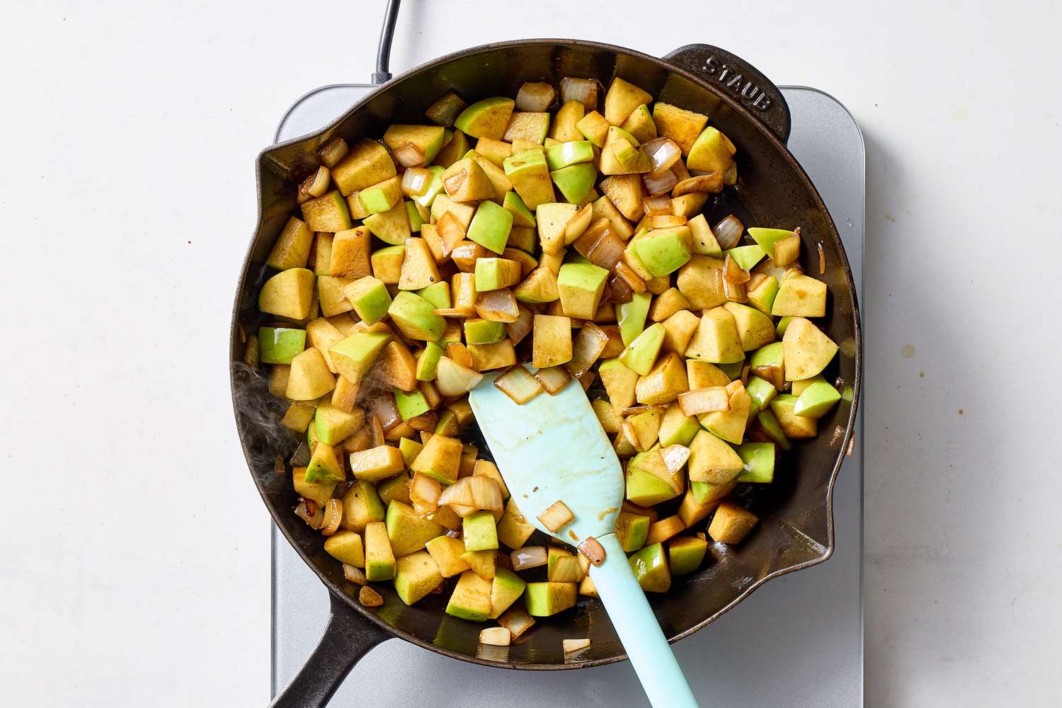 Cooking apple chunks in a pan being stirred with a spatula