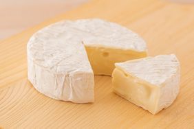 A wheel of soft cheese with a wedge cut out