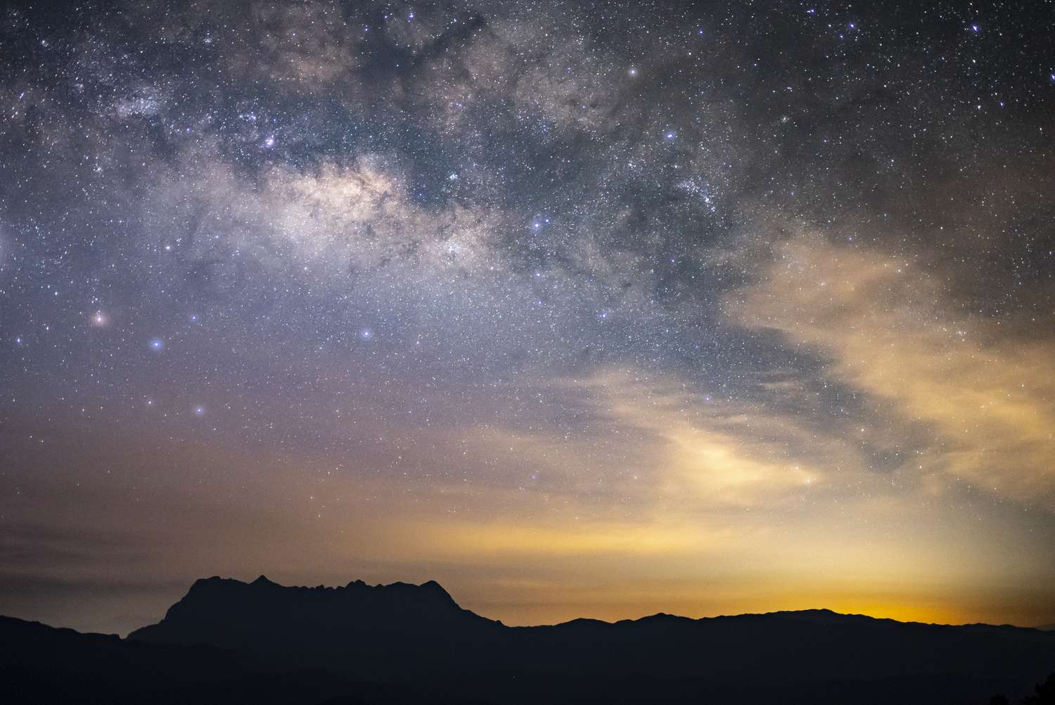 The Milky Way galaxy visible in the night sky above a silhouetted mountain range