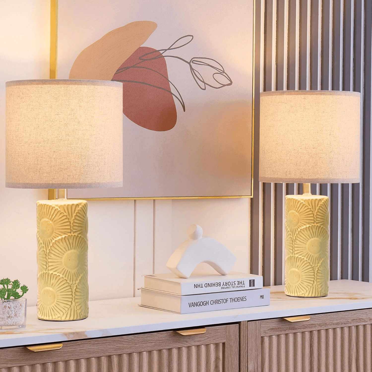 Two decorative table lamps on a modern console with books and artwork in the background