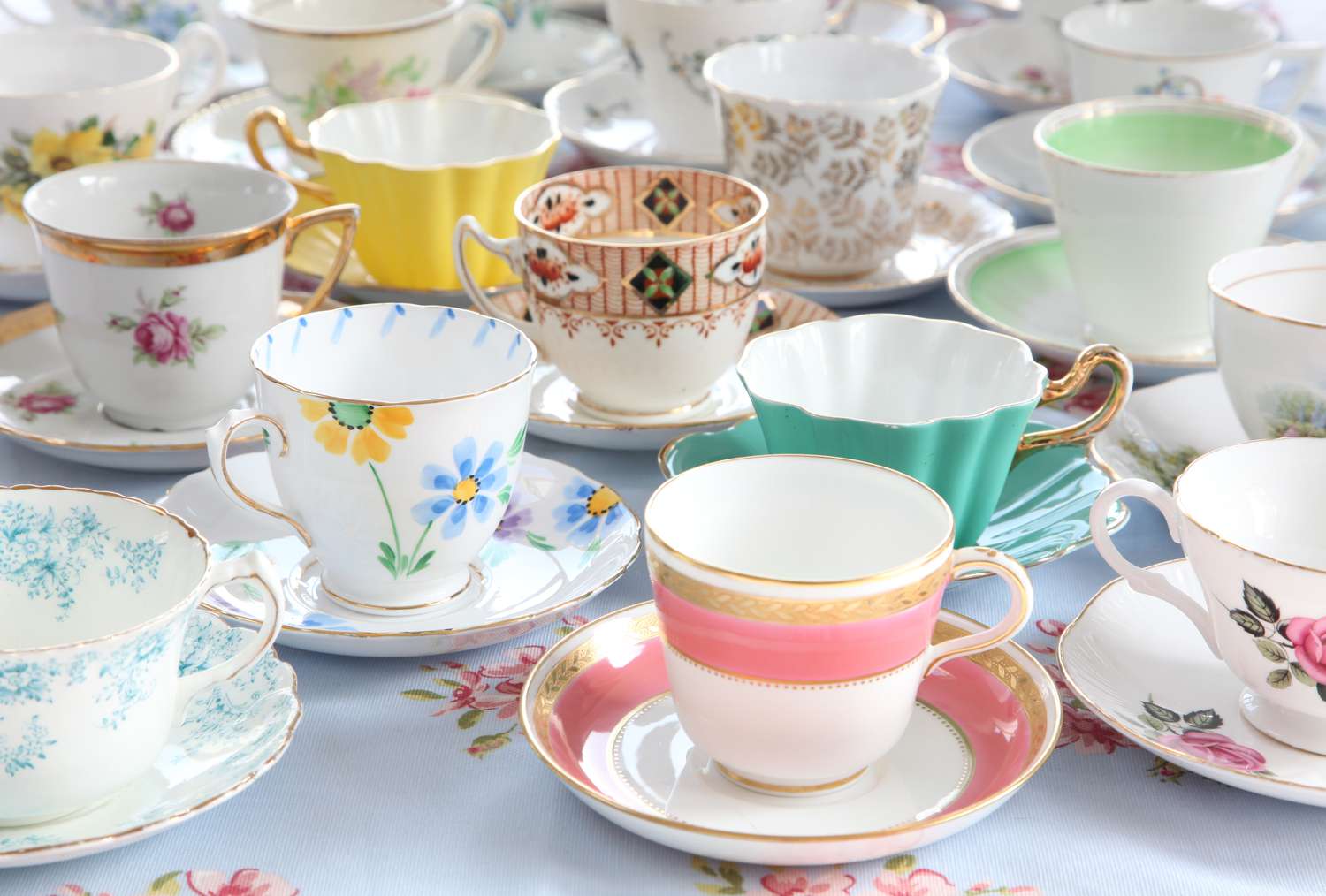 Various decorative teacups and saucers arranged on a table
