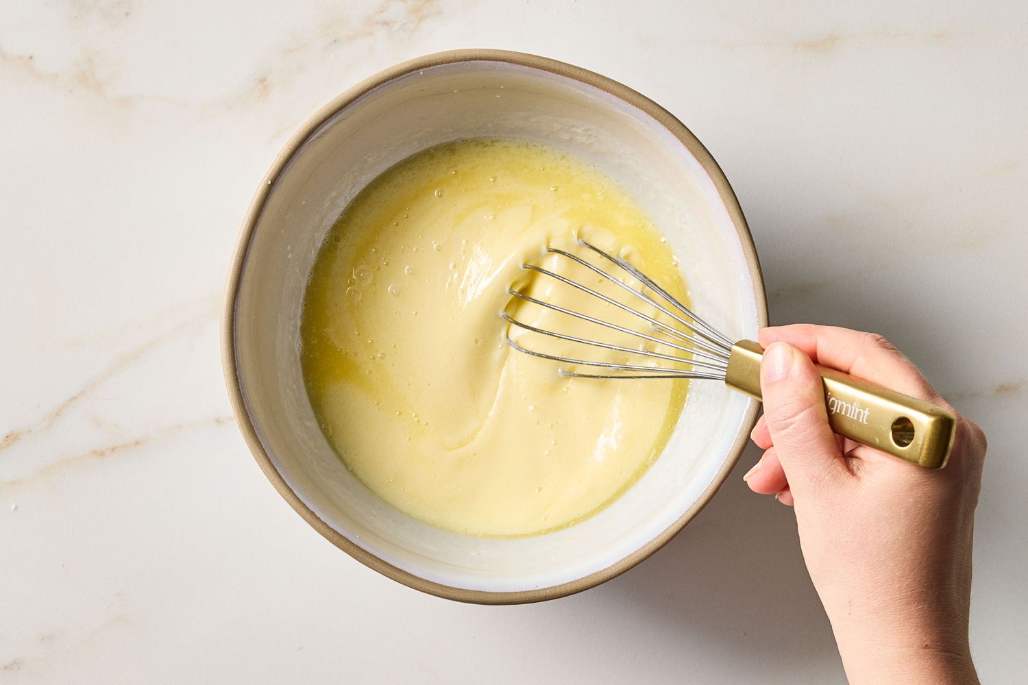 A hand whisking batter in a bowl