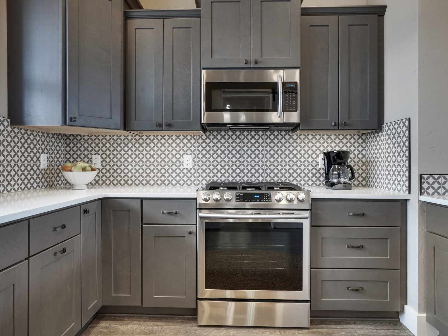 Modern kitchen with dark cabinets stainless steel appliances and patterned tile backsplash