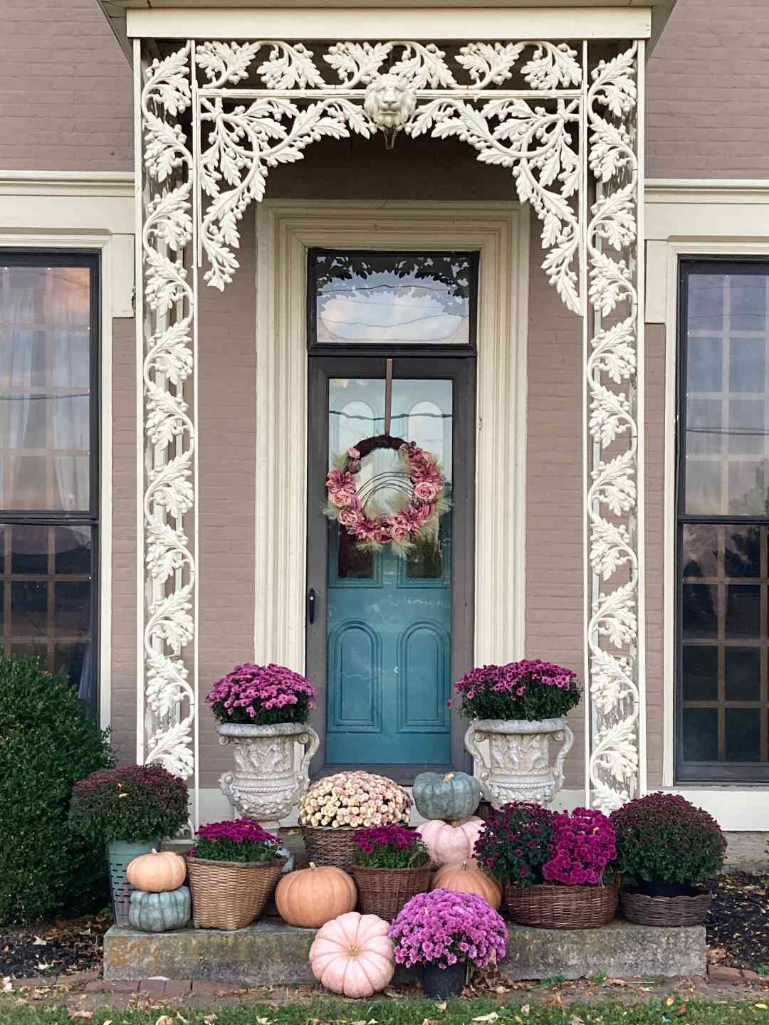 fall porch with purple mums and pumpkins