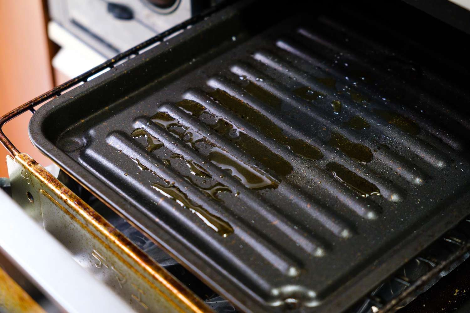 A greasy broiler pan inside an oven