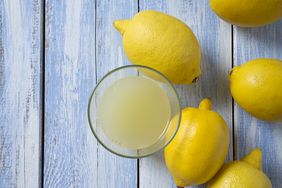 lemons and glass bowl of lemon juice on blue wood surface