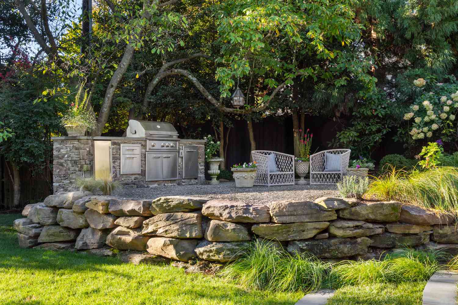 an elevated stone and gravel patio with seating area and outdoor kitchen 