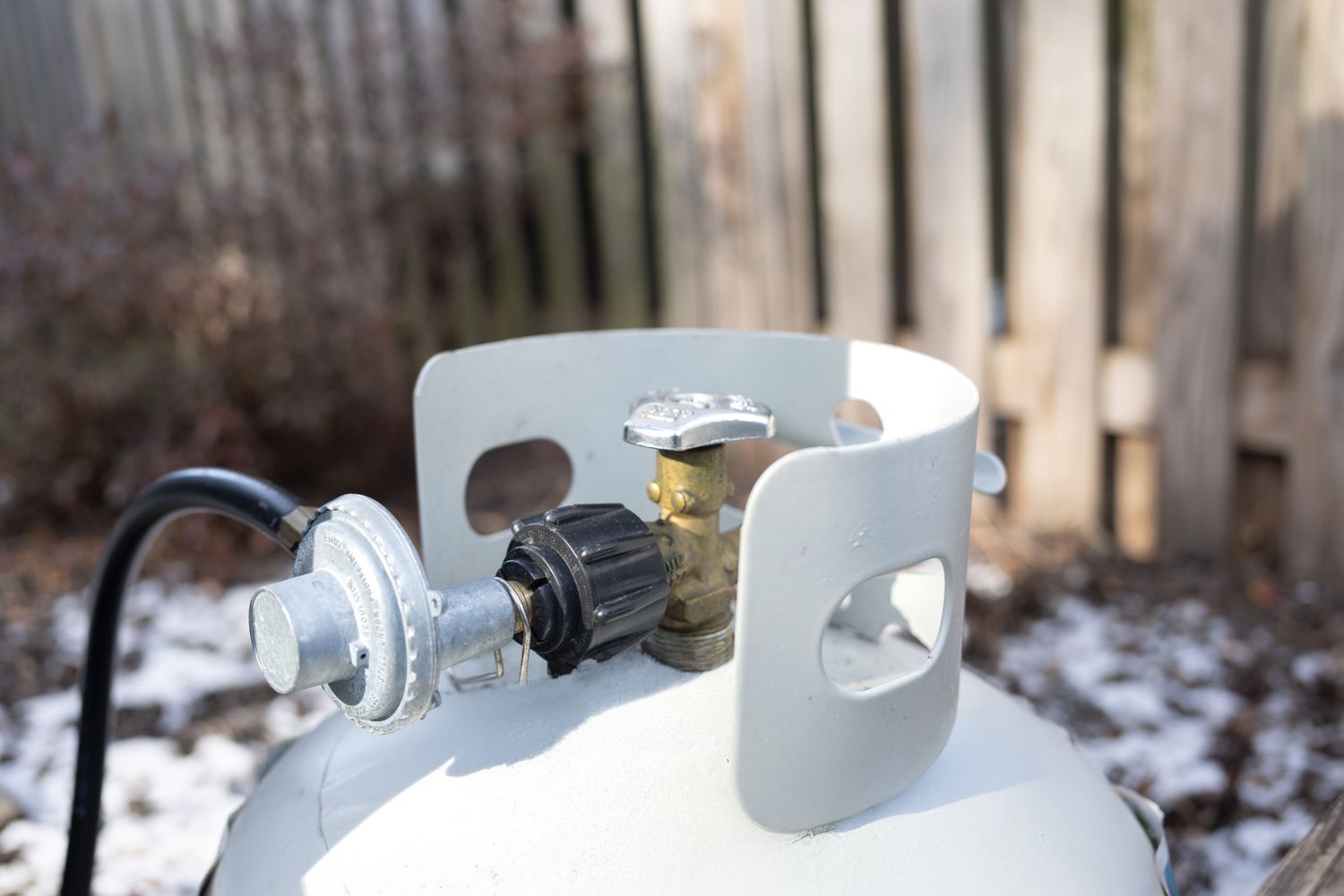 Propane tank with a valve and hose connection in an outdoor setting