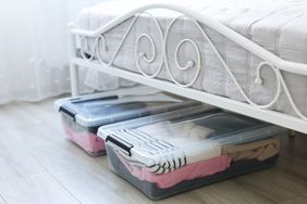 Plastic storage boxes filled with clothing under a metalframed bed