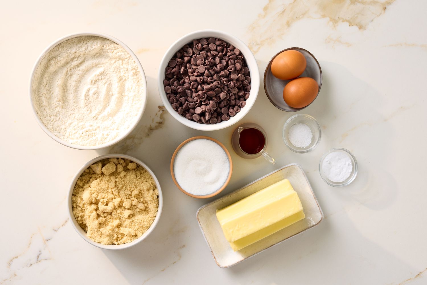 Ingredients for chocolate chip cookie bars including flour sugar chocolate chips butter eggs vanilla and baking powder