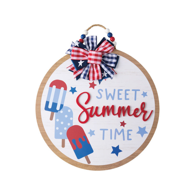 A round sign with popsicle illustrations and the words Sweet Summer Time decorated with a red white and blue bow
