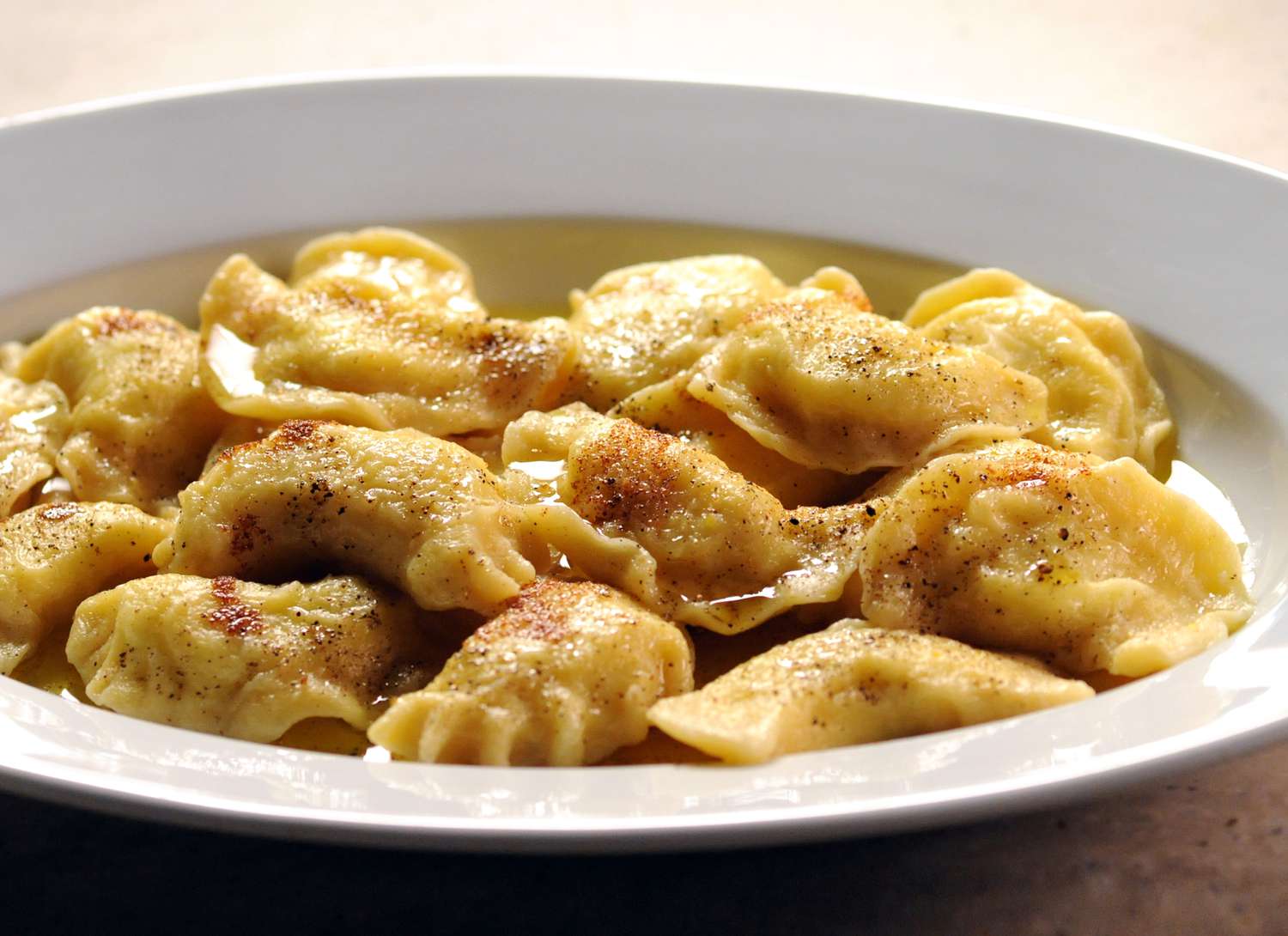 close up of bowl of dumplings gnocchi on a brown surface
