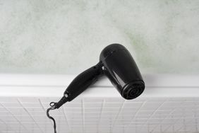 A hair dryer placed on the edge of a bathtub