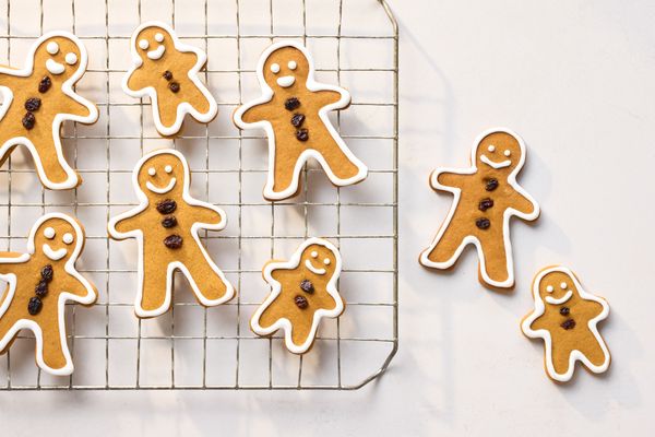 Gingerbread men cookies with icing and raisin decorations on a cooling rack