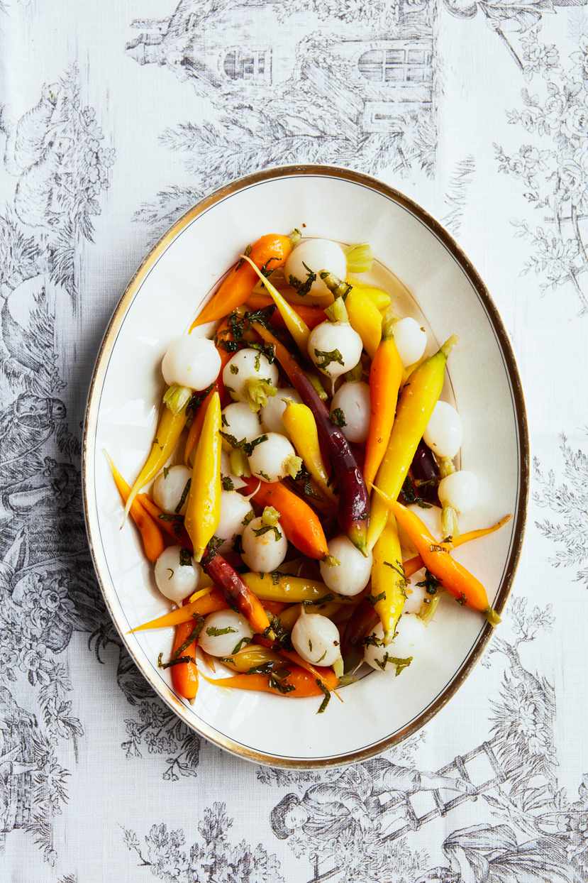 tender carrots and turnips with mint dressing atop toile pattern tablecloth