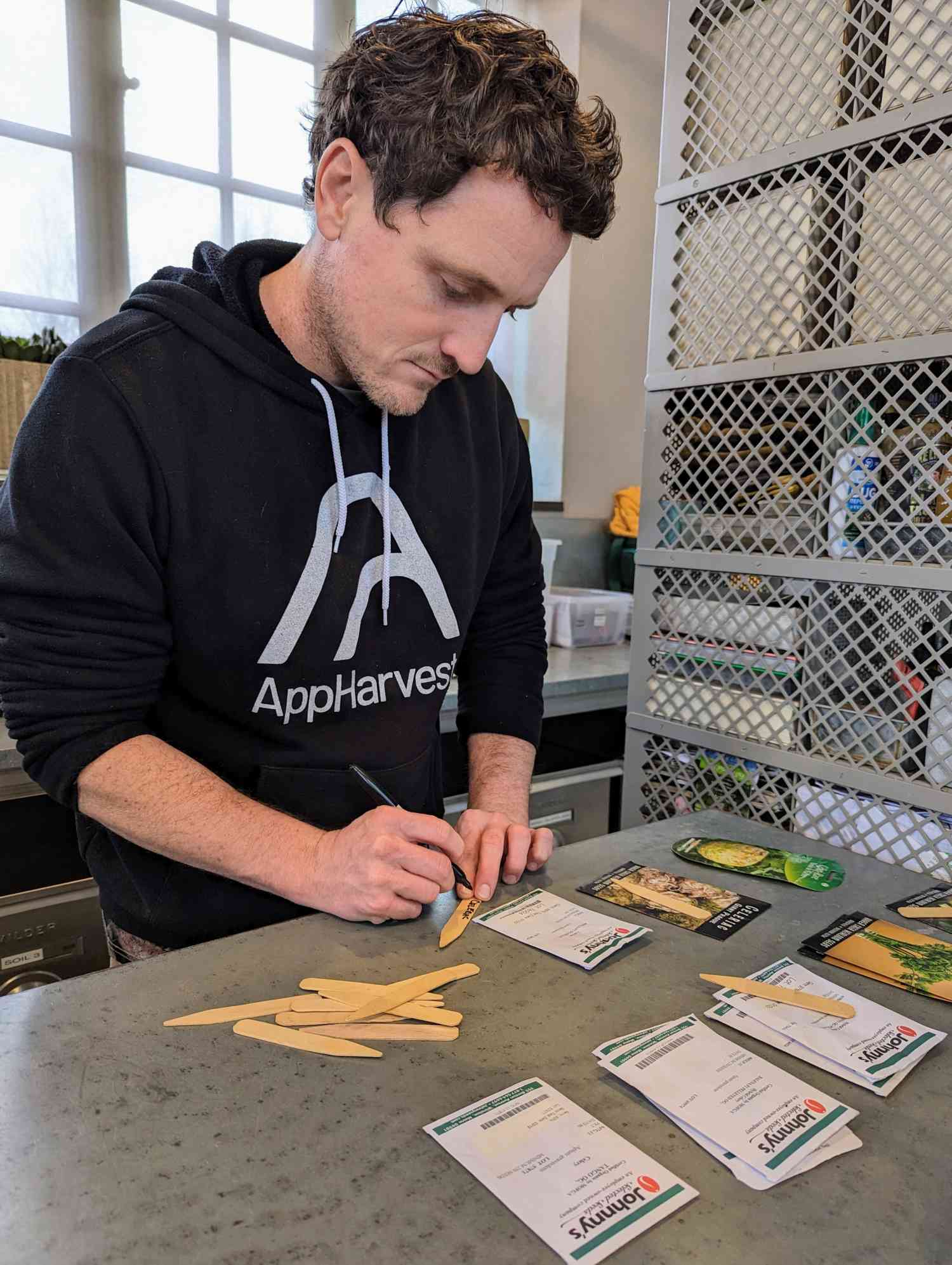Ryan McCallister writing on sticks for gardening
