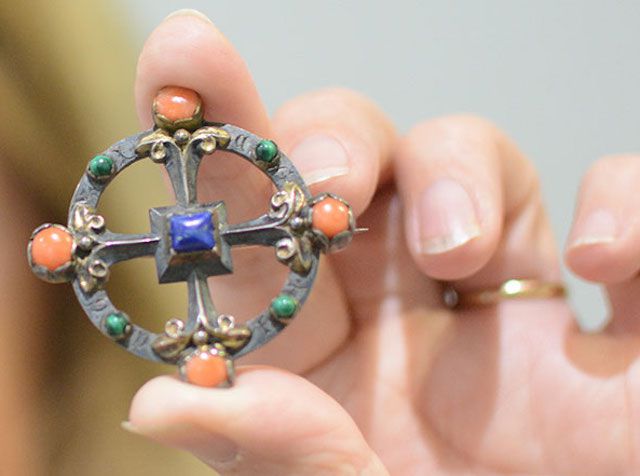 Person holding antique brooch