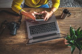 woman uploading photos from phone onto a laptop