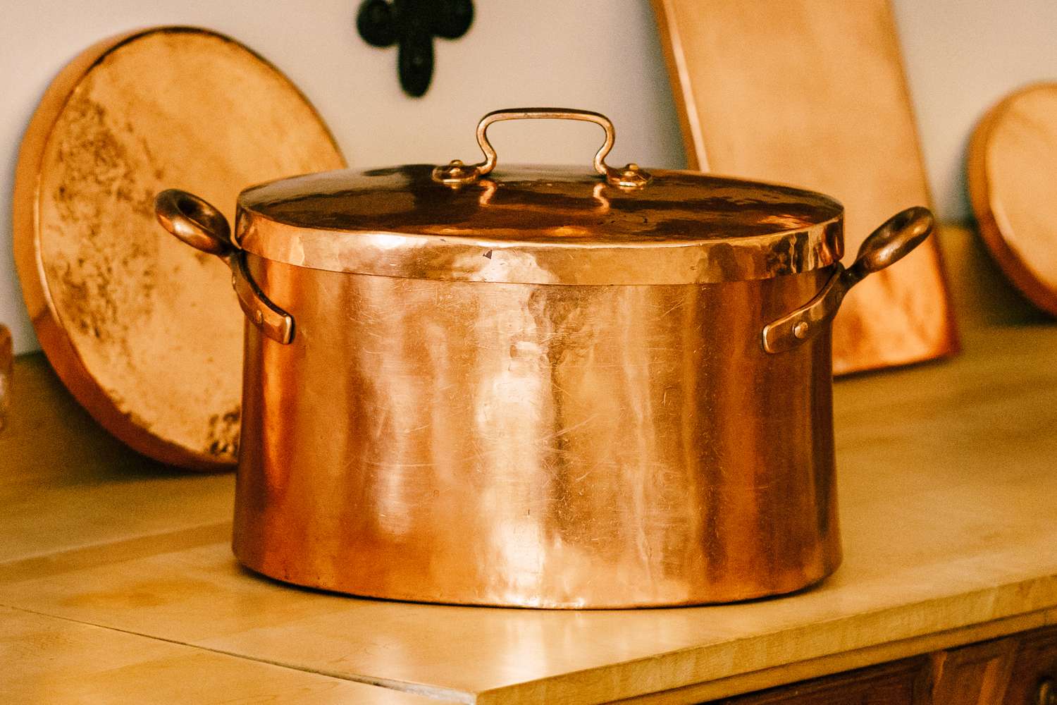 Copper cooking pot with handles and lid on a kitchen counter