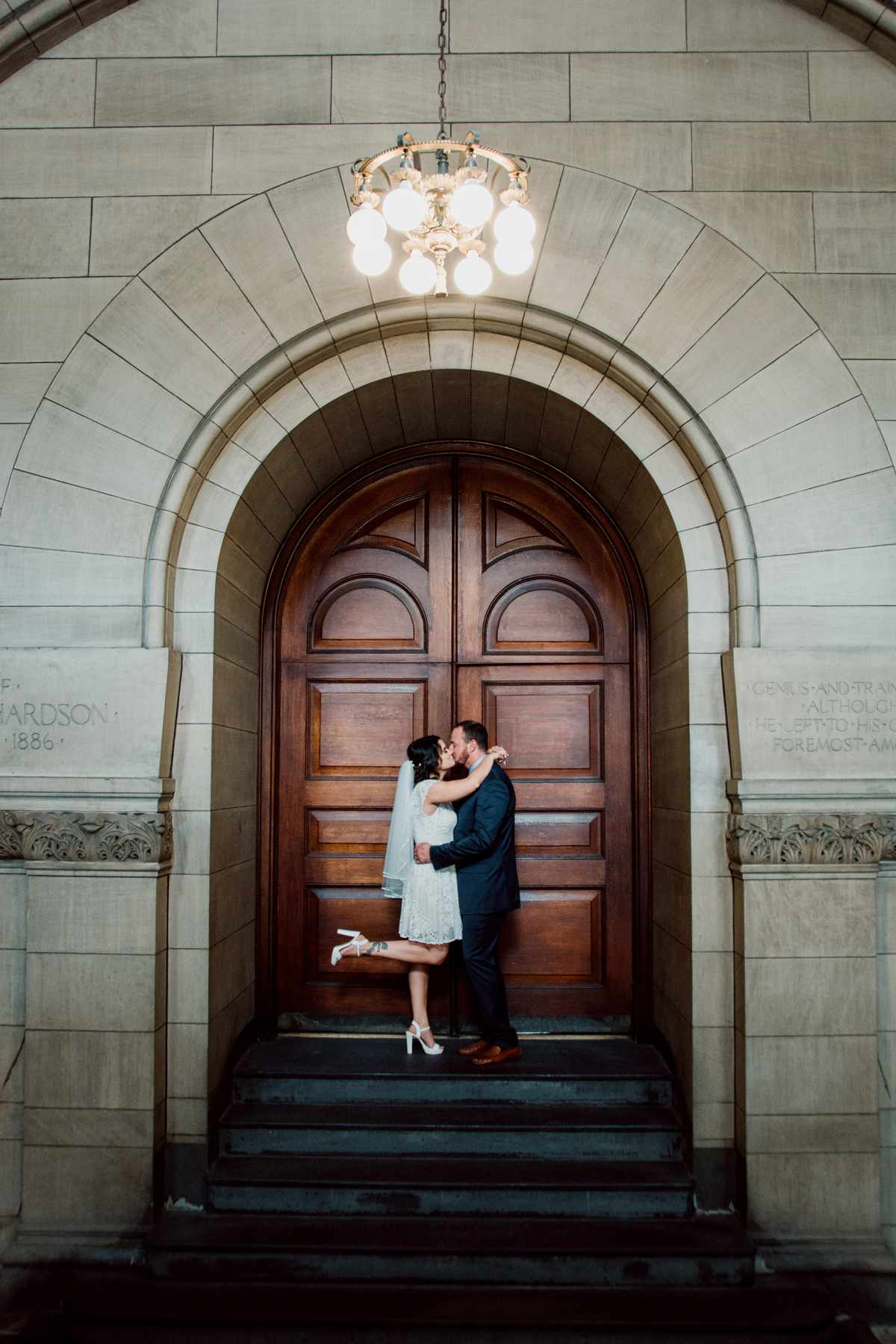 city hall wedding bride and groom kissing in front of wooden door