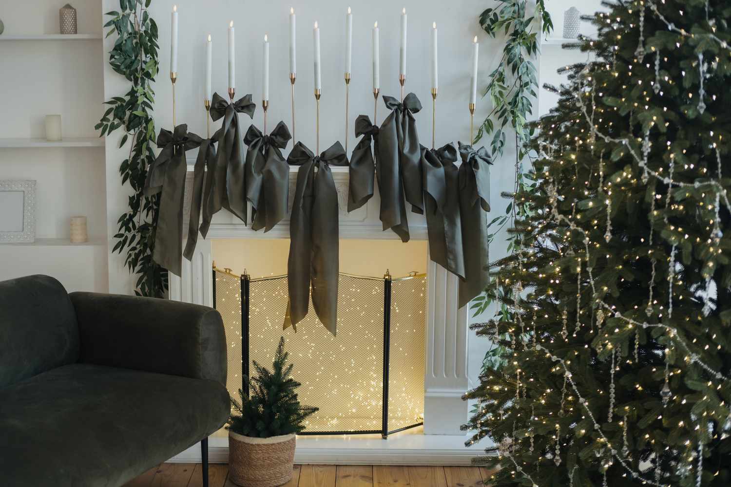 Christmas decorations featuring bows a lit tree and a mantel adorned with candles and greenery