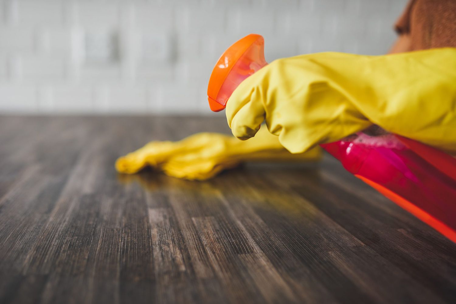 woman cleaning kitchen countertop with gloves on