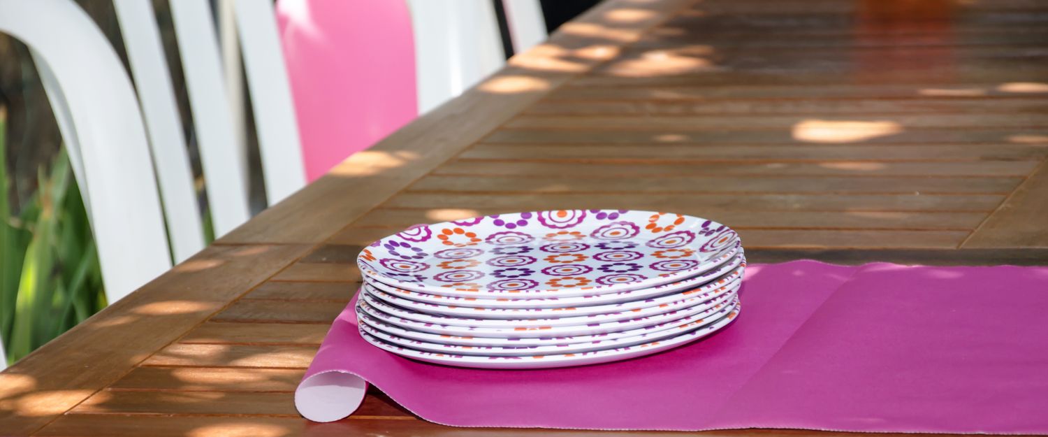 Stack of patterned plates placed on a wooden table with a tablecloth