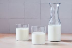 A carafe and two glasses of milk on a table